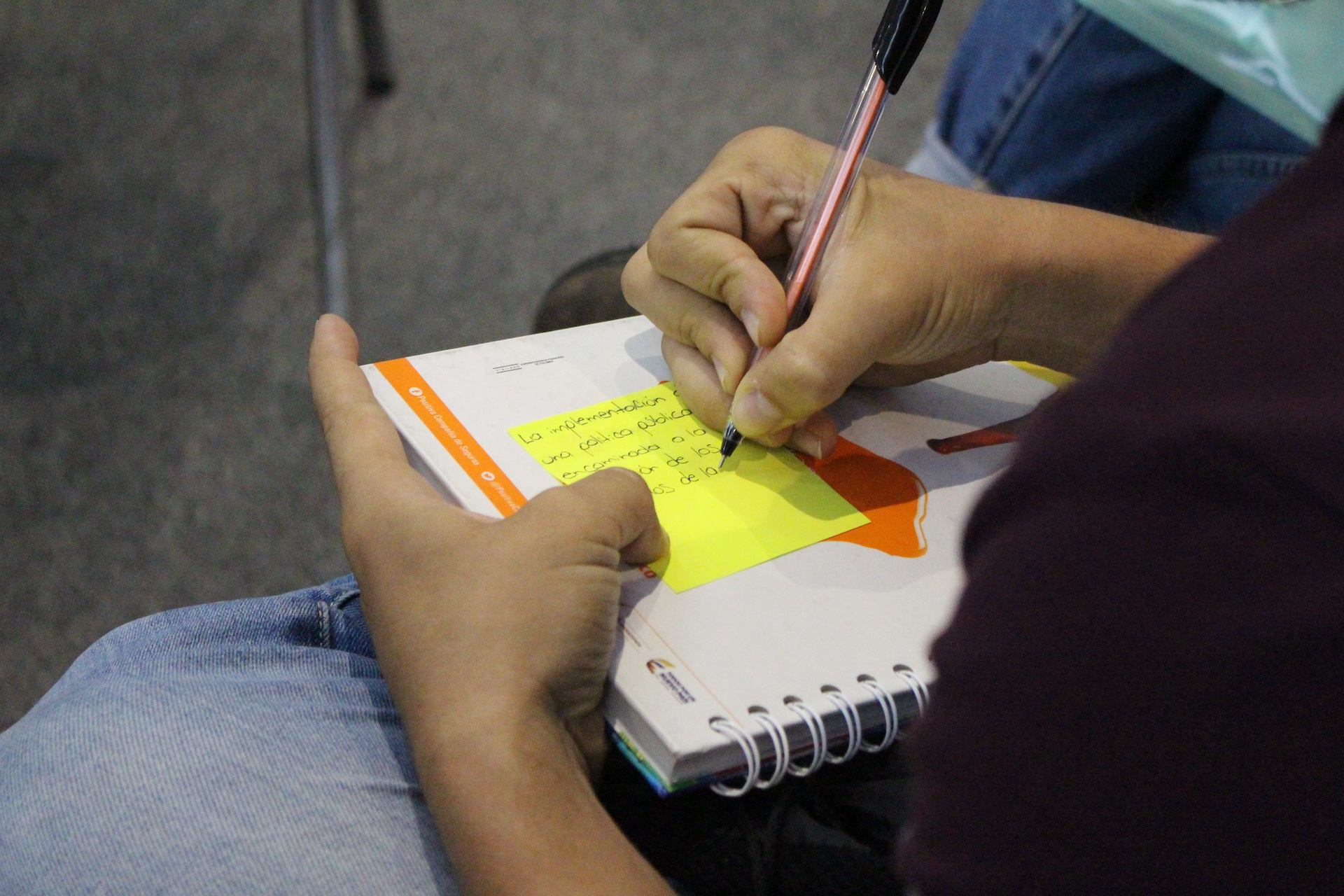 Mano de una persona sosteniendo un lapicero y escribiendo en un cuaderno