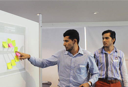 Hombre señalando unas notas adhesivas pegadas sobre un papel en la pared